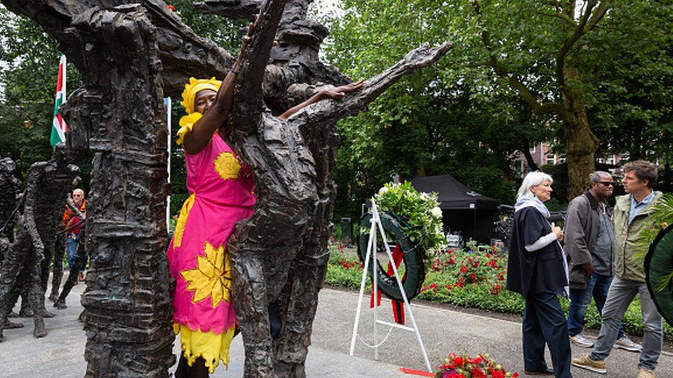 A woman poses behind a memorial at an event to mark Keti Koti in the Oosterpark in Amsterdam