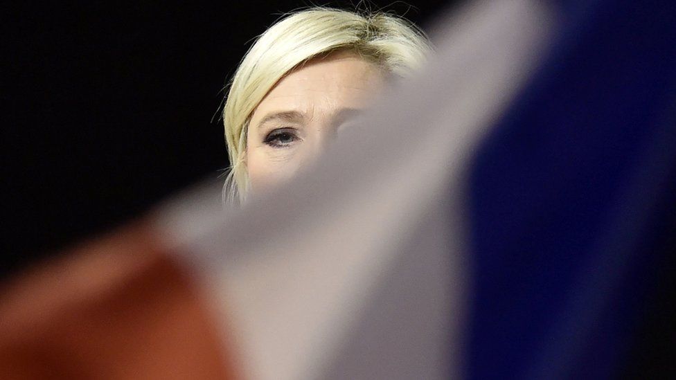 French presidential election candidate for the far-right Front National (FN) party, Marine Le Pen is seen behind a national flag as she speaks during a campaign rally on April 15, 2017 in Perpignan, southwestern France