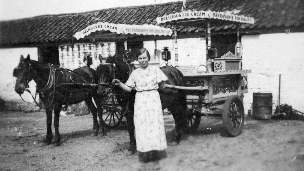 Black and white photo of woman by ice cream carriage