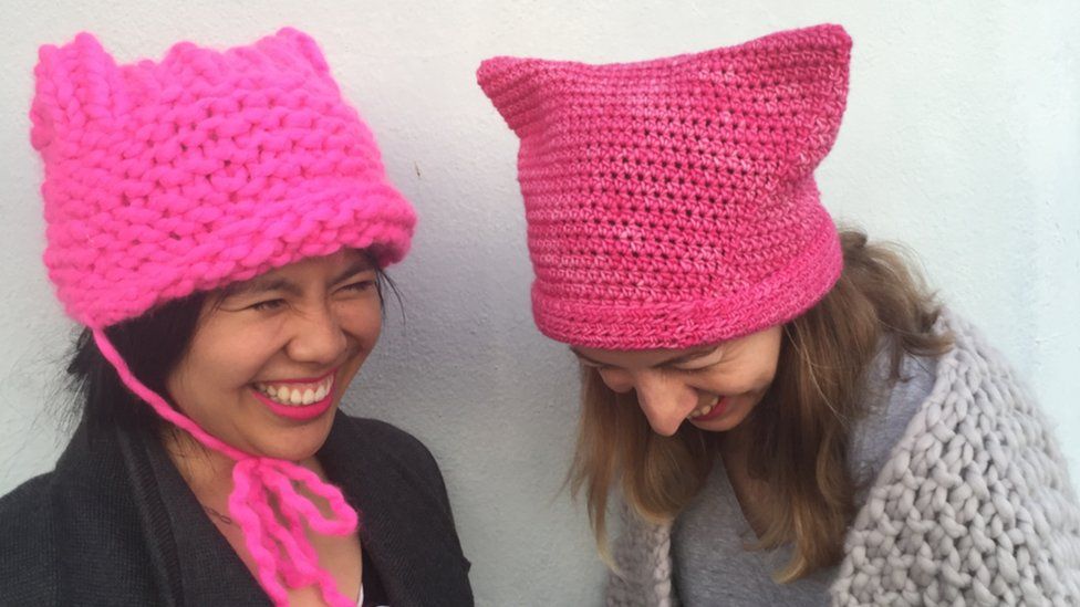 Pussyhat Project co-founders Krista Suh and Jayna Zweiman are seen laughing - wearing their hats