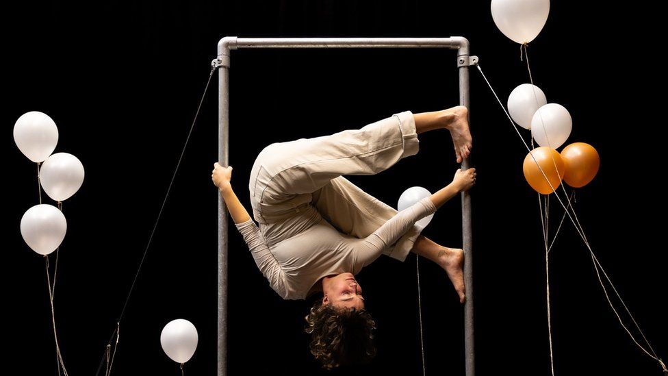 A woman upside down holding herself on metal bars as she rehearses for a Circomedia show in Bristol