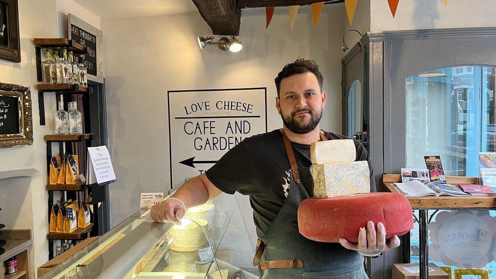 Man stood in shop holding cheese