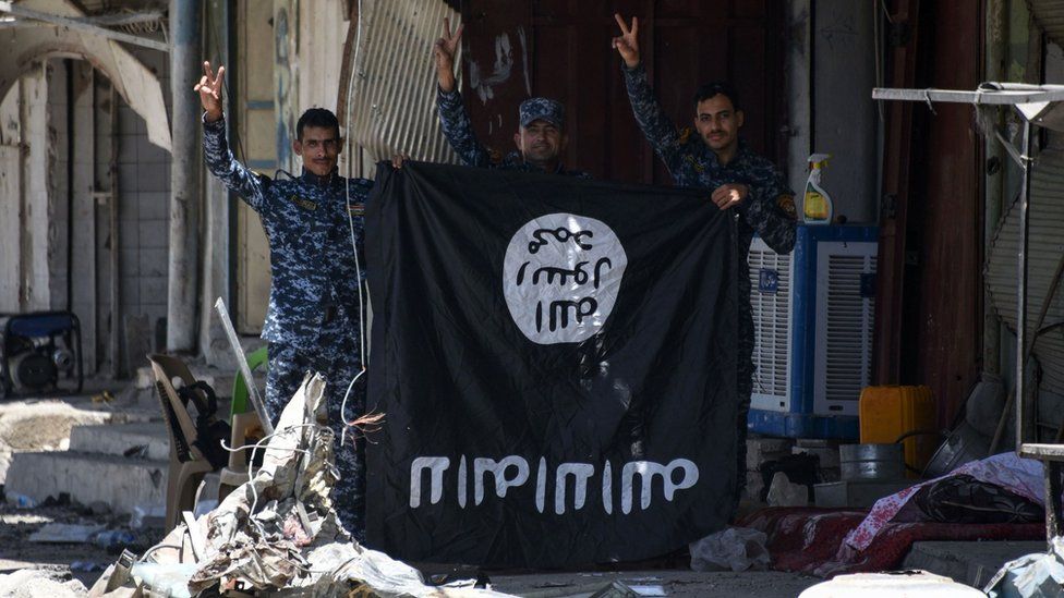 Iraqi government forces flash victory signs while holding an Islamic State (IS) group flag in western Mosul on 9 June 2017