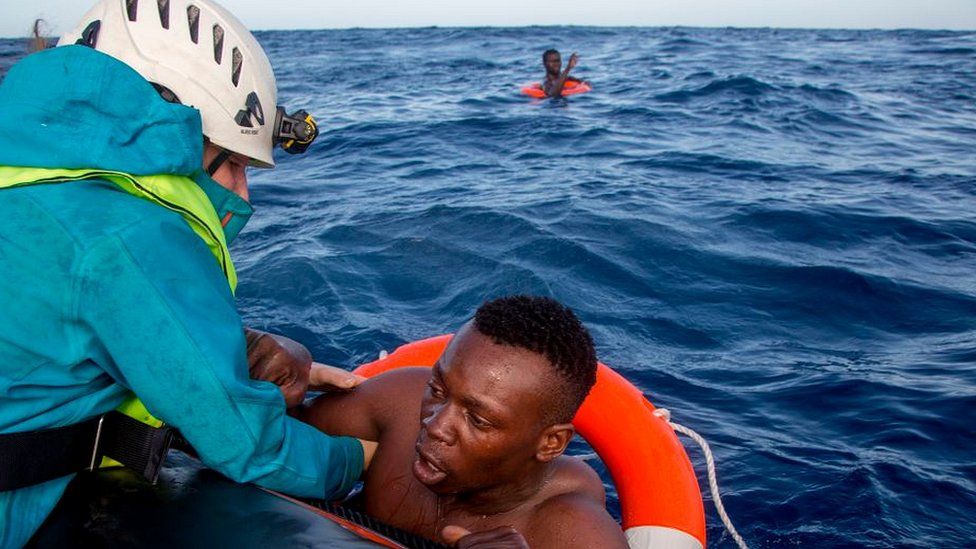 Rescue worker pulling migrant out of sea