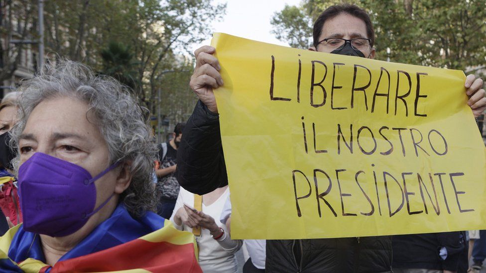 A demonstrator holds a banner reading in Italian language "Free Our President" as several dozens people rally in front of Italian Consulate