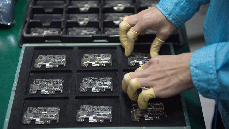 A worker checks chip component circuits at a factory in China