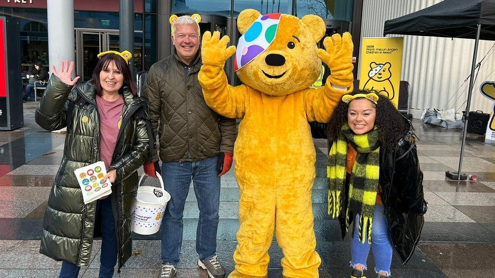 Woman with weatherman Derek Brockway stood next to Pudsey bear and Radio Wales DJ Aleighcia Scott