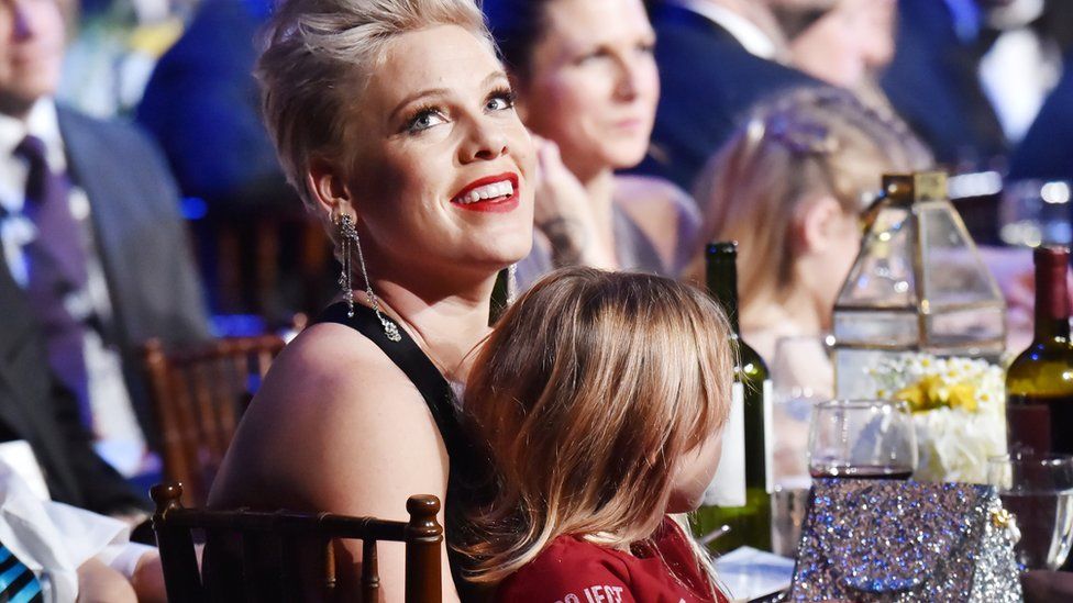 Pink sits in a chair with her daughter sat on her lap