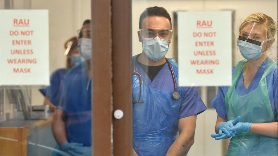 Medical staff wearing personal protective equipment (PPE) wait to receive coronavirus patients at the door of the Respiratory Assessment Unit at the Morriston Hospital in Swansea