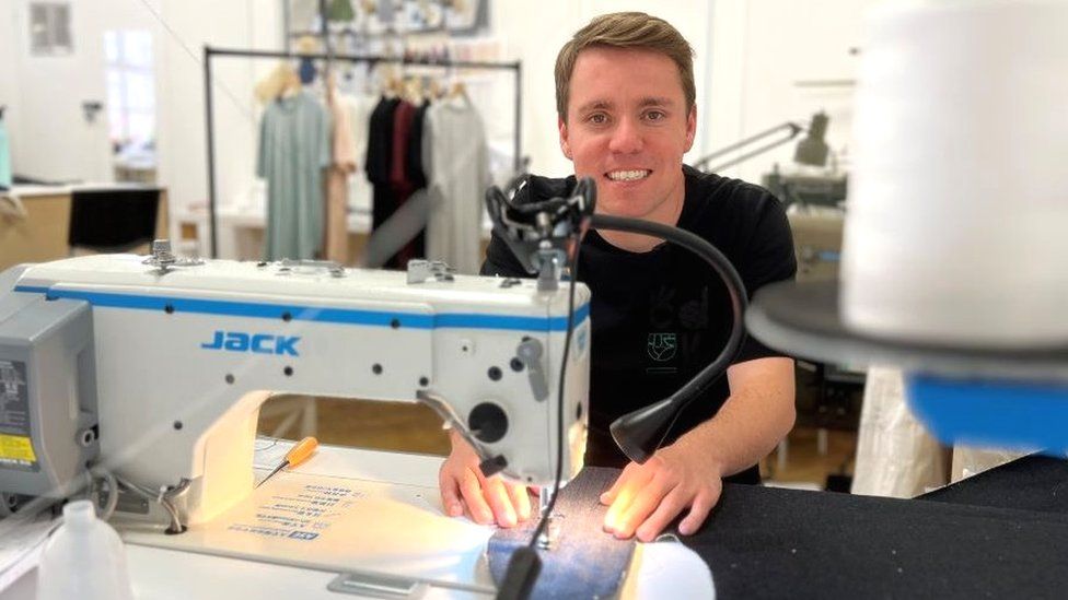 Stevie Mitchell sewing and looking at the camera