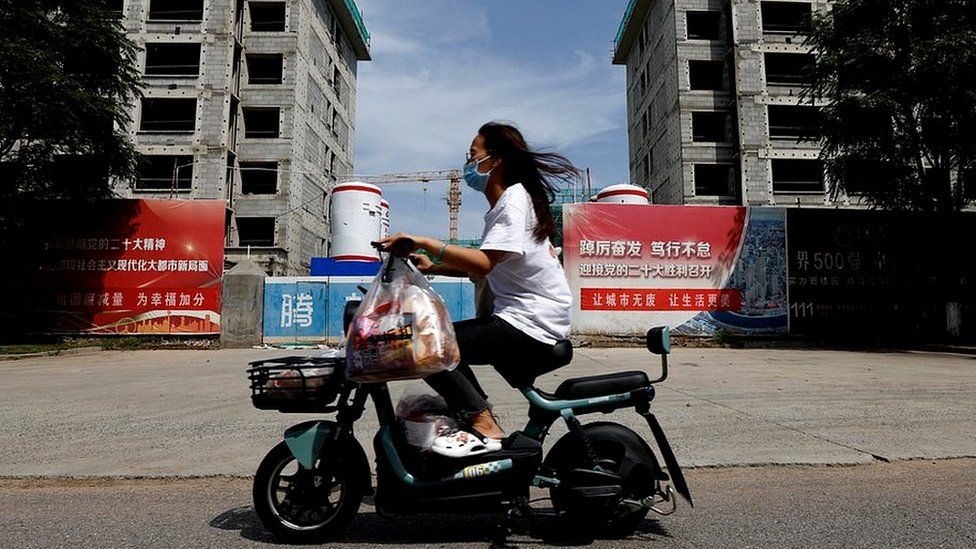 A person rides a scooter past a construction site of residential buildings by Country Garden in Tianjin, China.