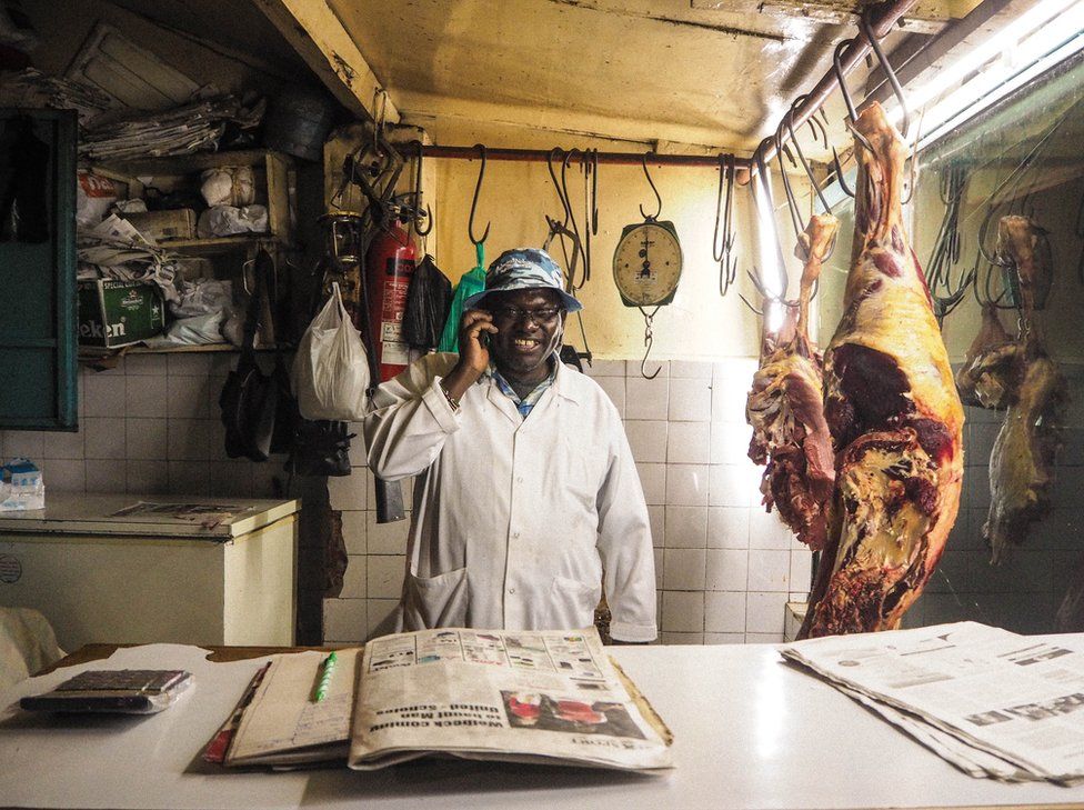 Kenya, 2014. A butcher uses his mobile phone.