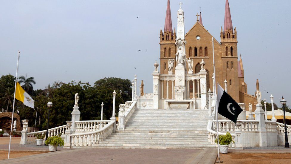 The flags of Vatican City and Pakistan flying at half mast outside the church