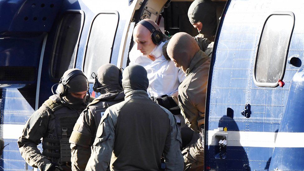 A person believed to be the suspect in the Halle shooting is assisted by policemen to get out of a helicopter after it landed at the Federal Supreme Court (Bundesgerichtshof) in Karlsruhe, southern Germany, on October 10, 2019