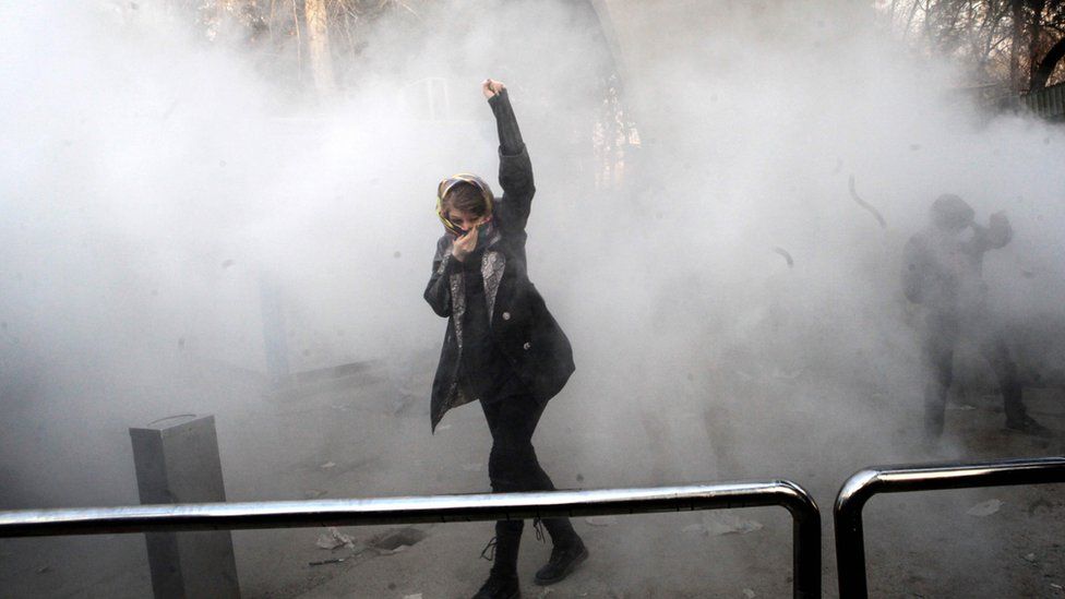 A protester raises her fist amid the smoke of tear gas