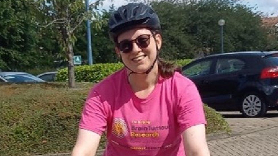 Woman in pink t-shirt and cycling helmet riding a bike