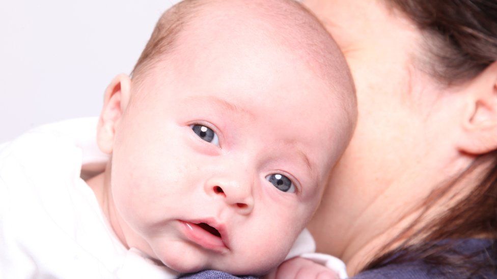 Baby being held by his mother, part of a couple from Ireland who travelled to Ukraine for surrogacy