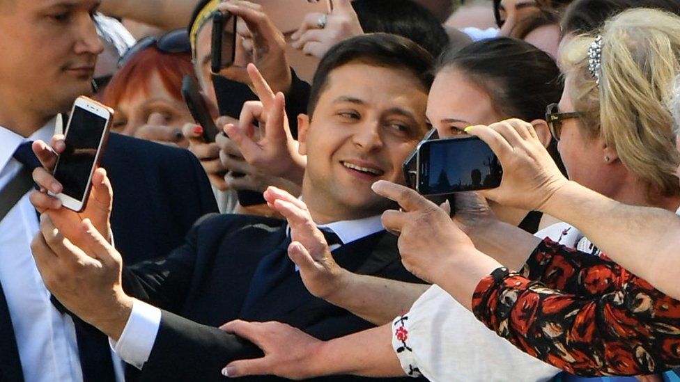 Zelensky takes a photo with a woman in the crowd