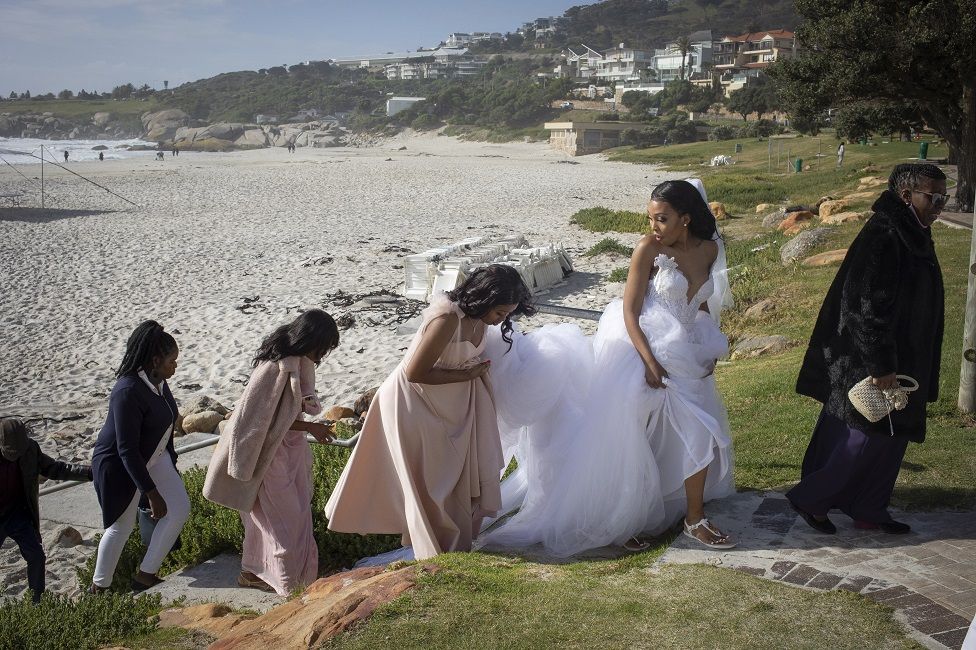 A bridal party walks up from the beach.