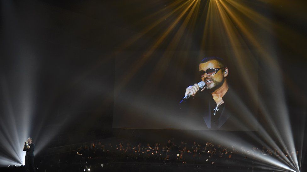 Chris Martin on stage with George Michael on a video screen