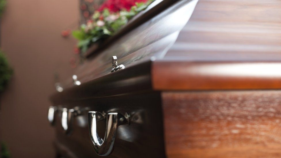 Close-up of a closed coffin and funeral flowers