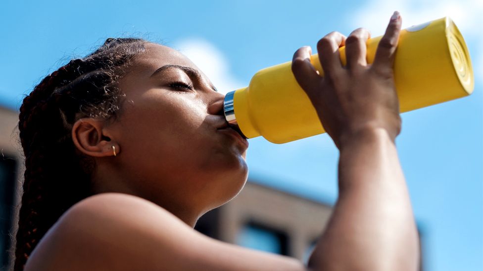 A woman drinks from a water bottle