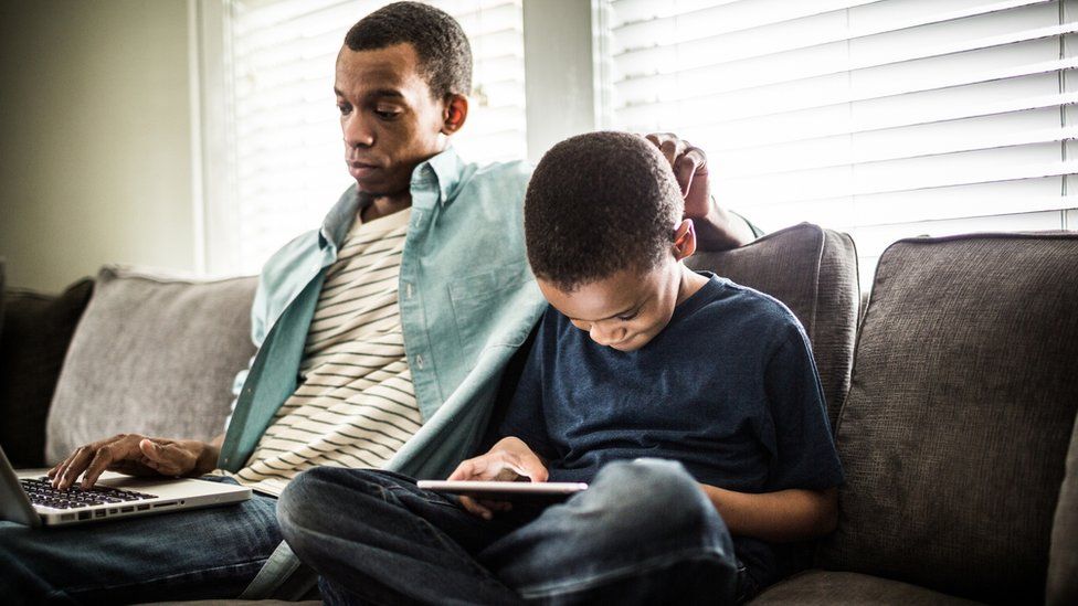 A stock image of father and son browsing online