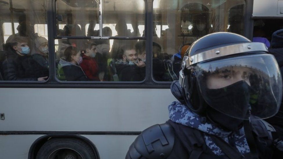 A policeman by a bus of detained protesters in St Petersburg