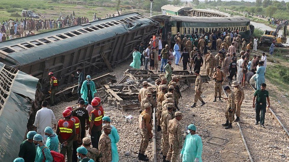 Paramilitary rangers and volunteers inspect the carriages at the accident site following the derailment of a passenger train in Nawabshah on August 6, 2023