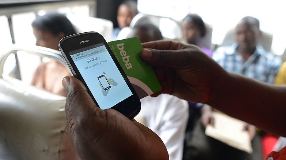 A Kenyan bus passenger uses a mobile phone-based money transfer service to pay their bus fare