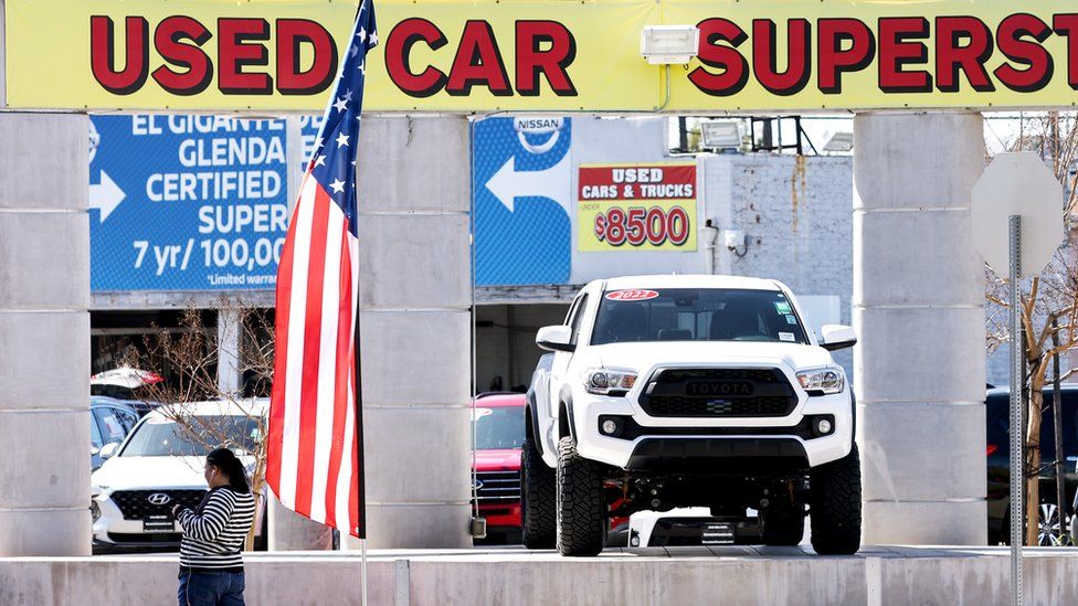 A pedestrian walks past a used car lot on February 15, 2023 in Glendale, California.