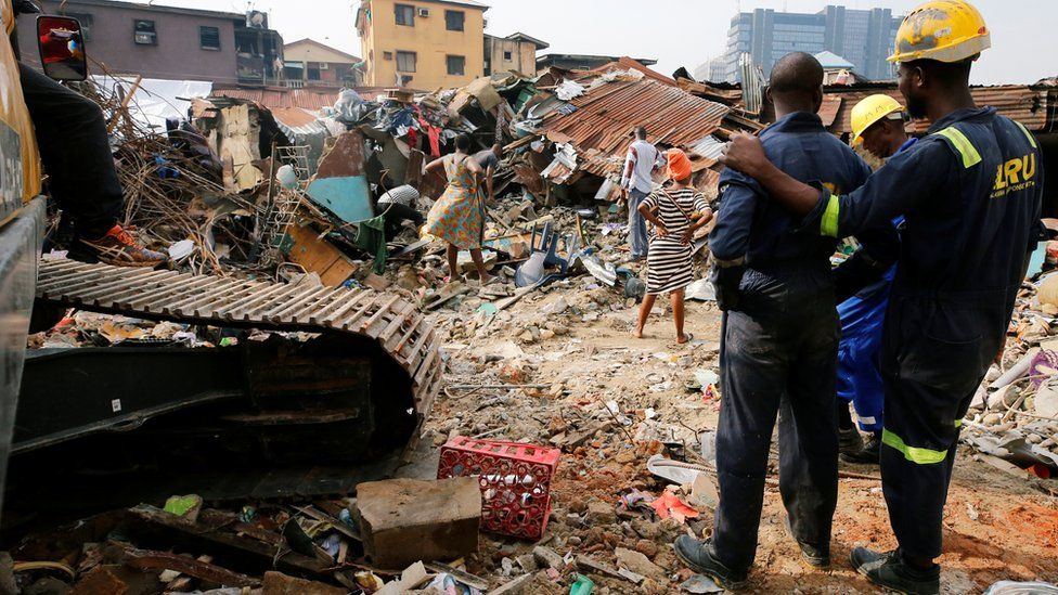 People looking on at a building that collapsed on Lagos island March 2019