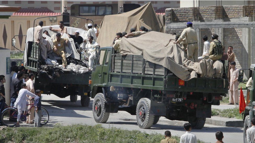 Soldiers and residents stand over covered debris as it is moved out by military vehicles from the compound within which al Qaeda leader Osama bin Laden was killed, in Abbottabad in this May 2, 2011