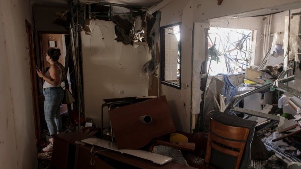 A woman walks inside her parents" apartment after it was hit with a rocket fired from Gaza, in Ashdod, Israel