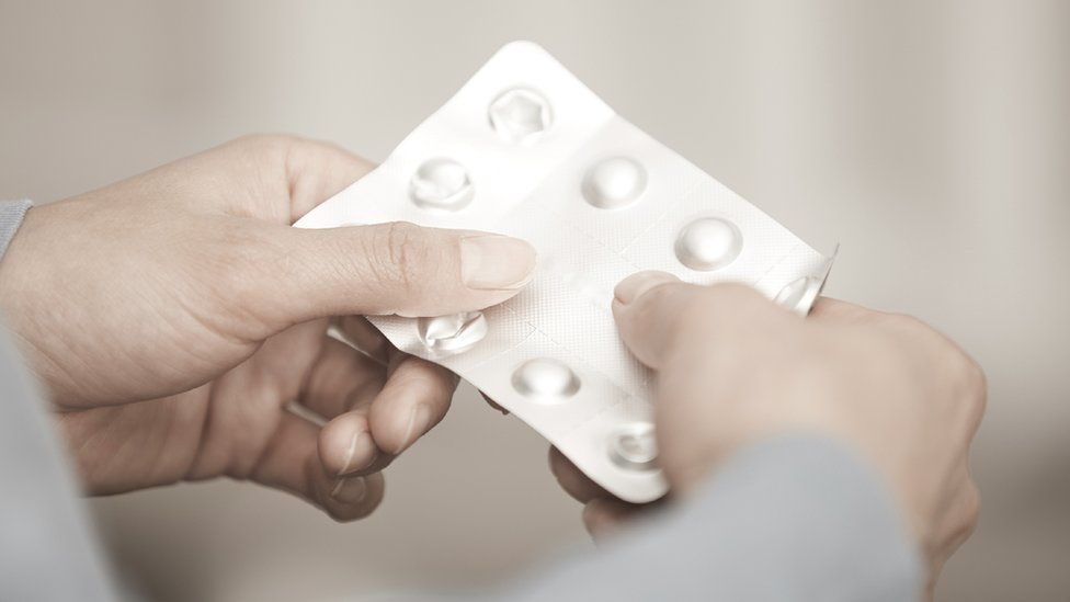 A woman holds a pill packet