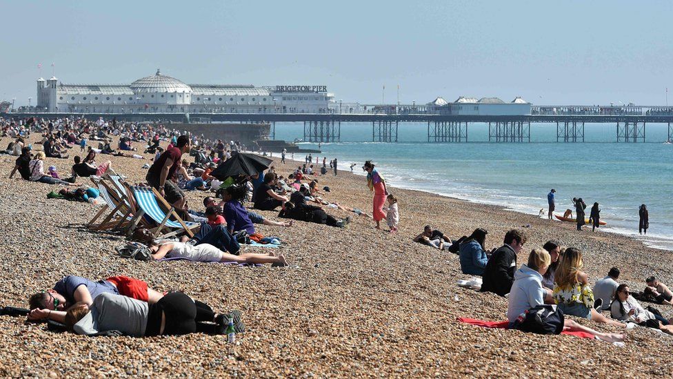 People enjoy the sunshine on Brighton beach