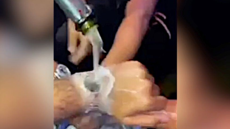 Still from video showing Champagne being poured over watches