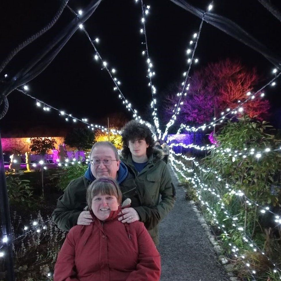Joanne, her husband Phillip and her son Mackenzie posing under some Christmas lights