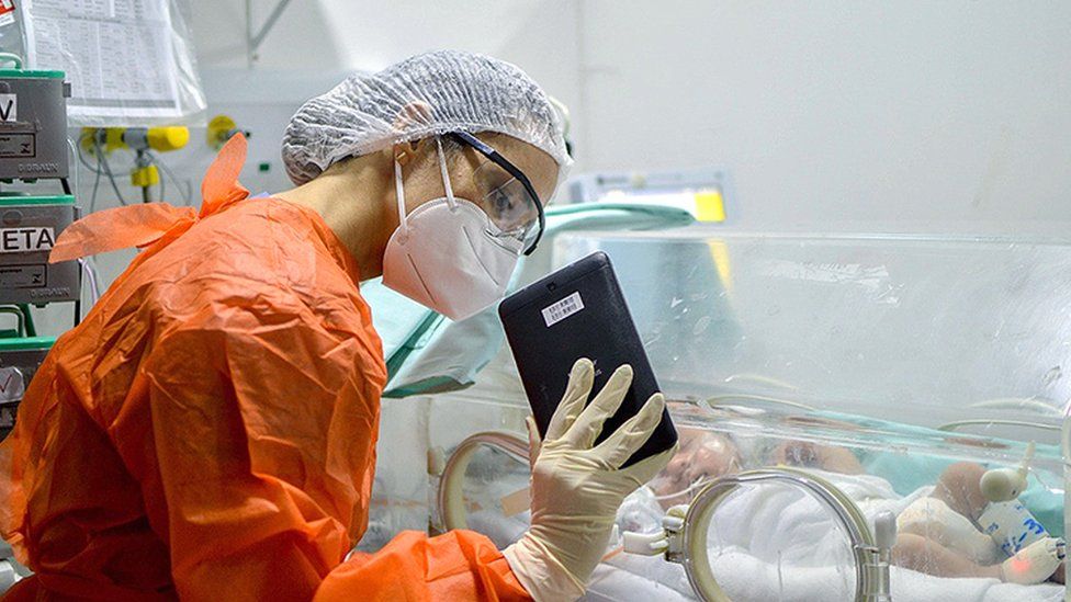 Um médico mostra um tablet para uma criança na UTI