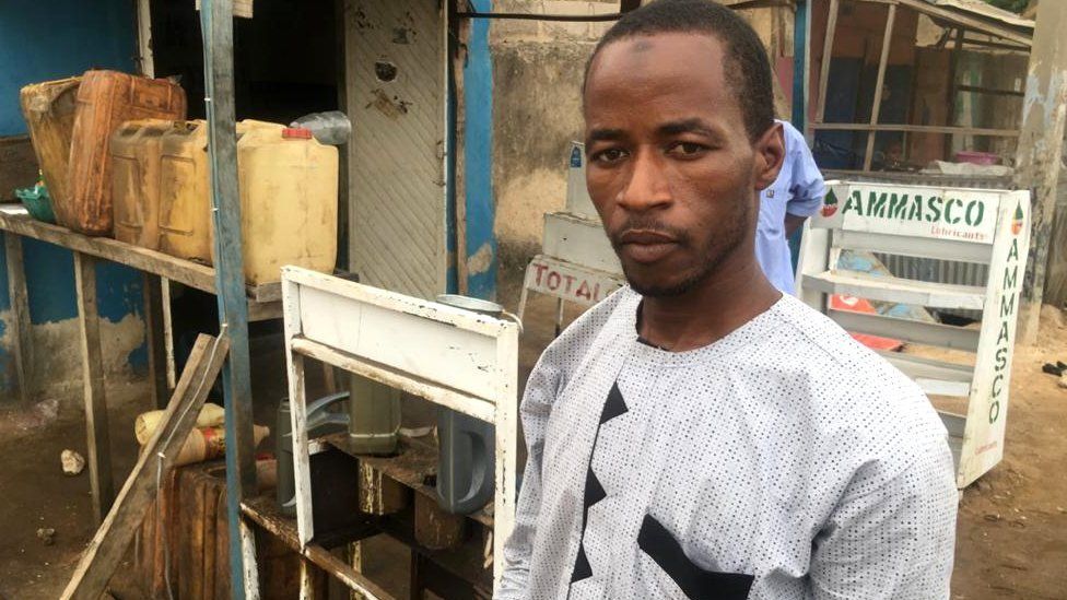 Former almajiri student standing in front of his gas shop