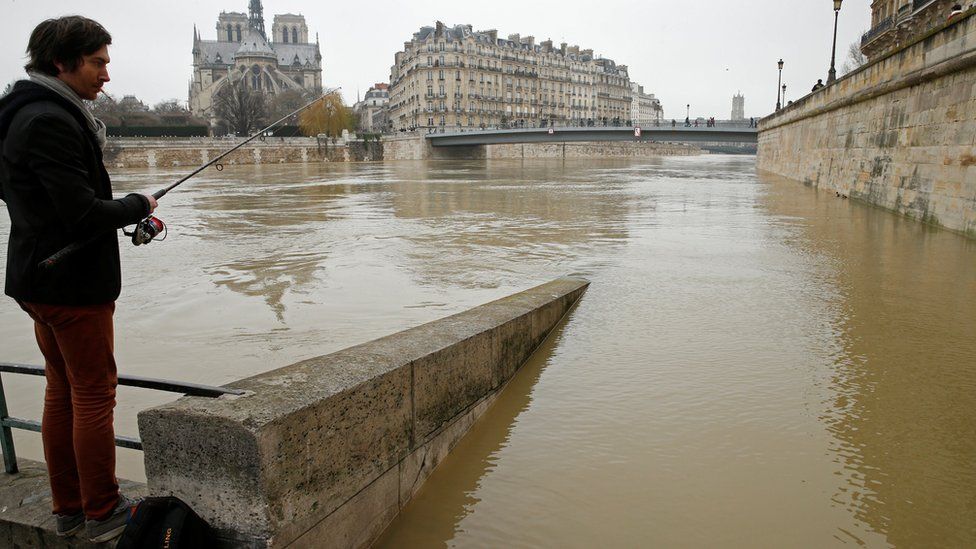 Мужчина ловит рыбу на затопленных берегах реки Сены в Париже, Франция, после нескольких дней почти непрекращающегося дождя, вызвавшего наводнение в стране, 27 января 2018 г.