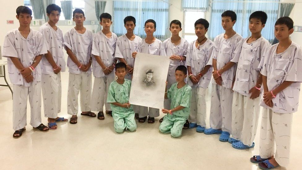 The 12-member "Wild Boars" soccer team and their coach rescued from a flooded cave pose with a drawing picture of Samarn Gunan, a former Thai navy diver who died working to rescue them, at Chiang Rai Prachanukroh Hospital