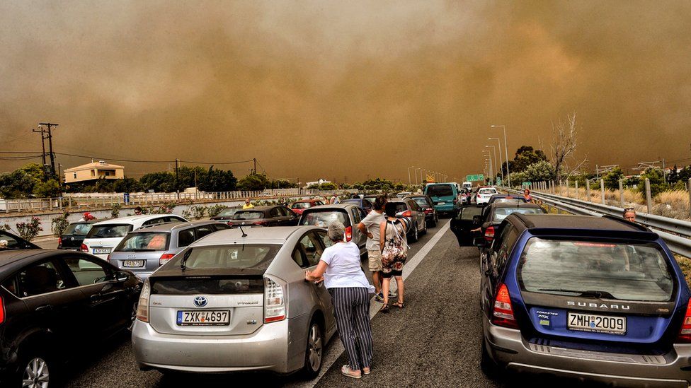 Cars are blocked at the closed National Road during a wildfire in Kineta, near Athens