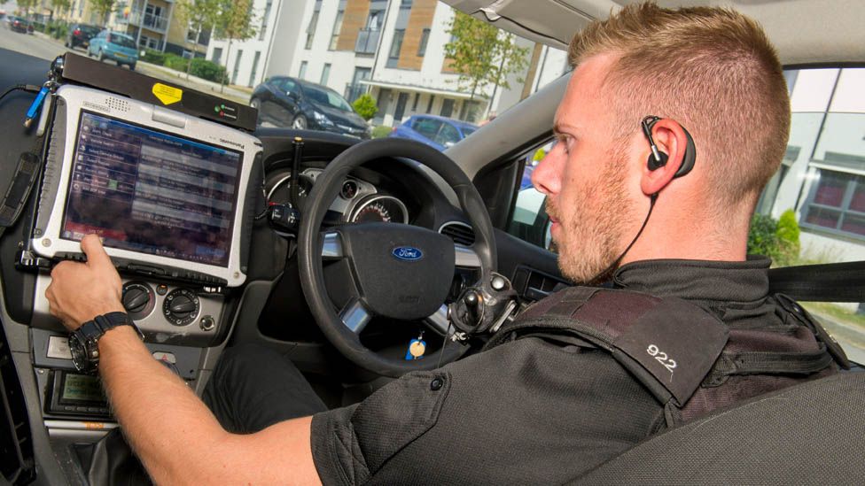 Police officer using a computer in a patrol car in Bristol