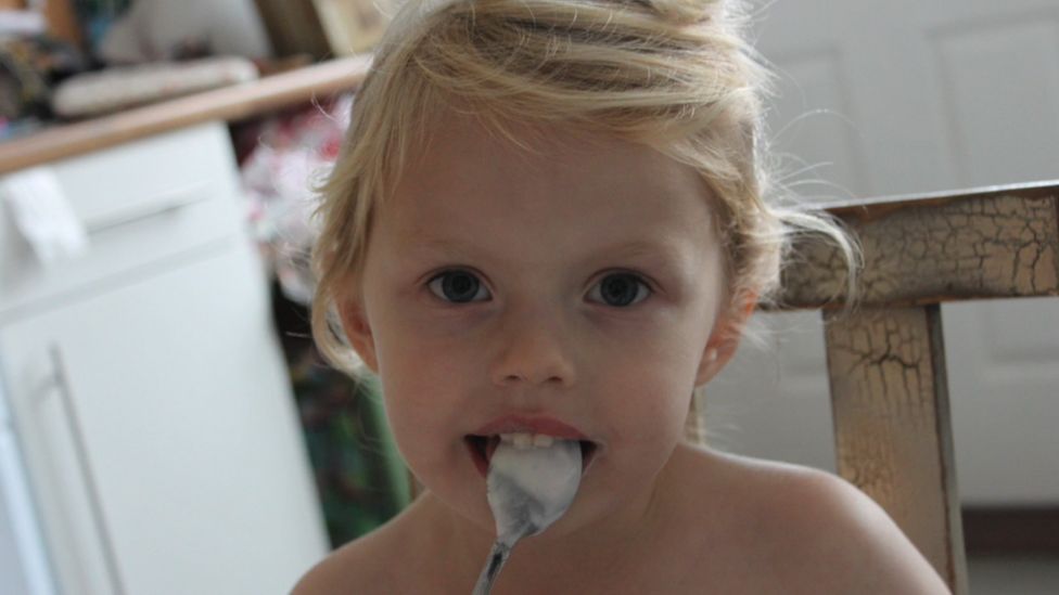 young girl with spoon in her mouth