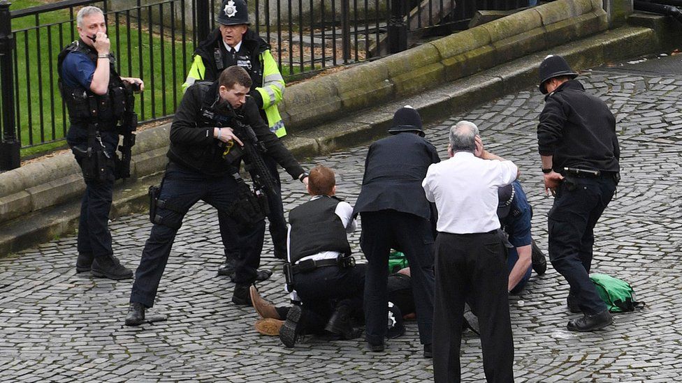 Police hold a gun to a man on the ground during Westminster attack