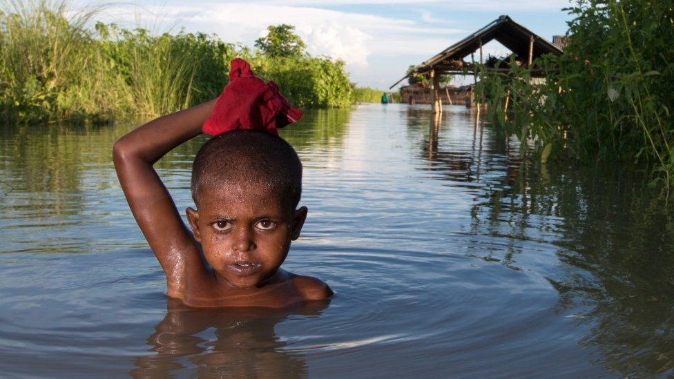 Мальчик стоит в паводковой воде в Бангладеш