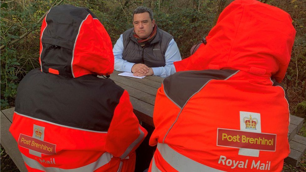 Reporter Aled Scourfield with two Royal Mail workers with their backs to the camera