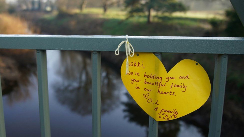 A yellow ribbon with a message of hope written on it tied to a bridge over the River Wyre in St Michael's on Wyre, Lancashire,