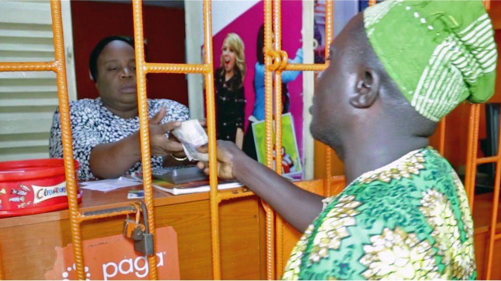 A man hands cash over at a kiosk in Lagos, Nigeria